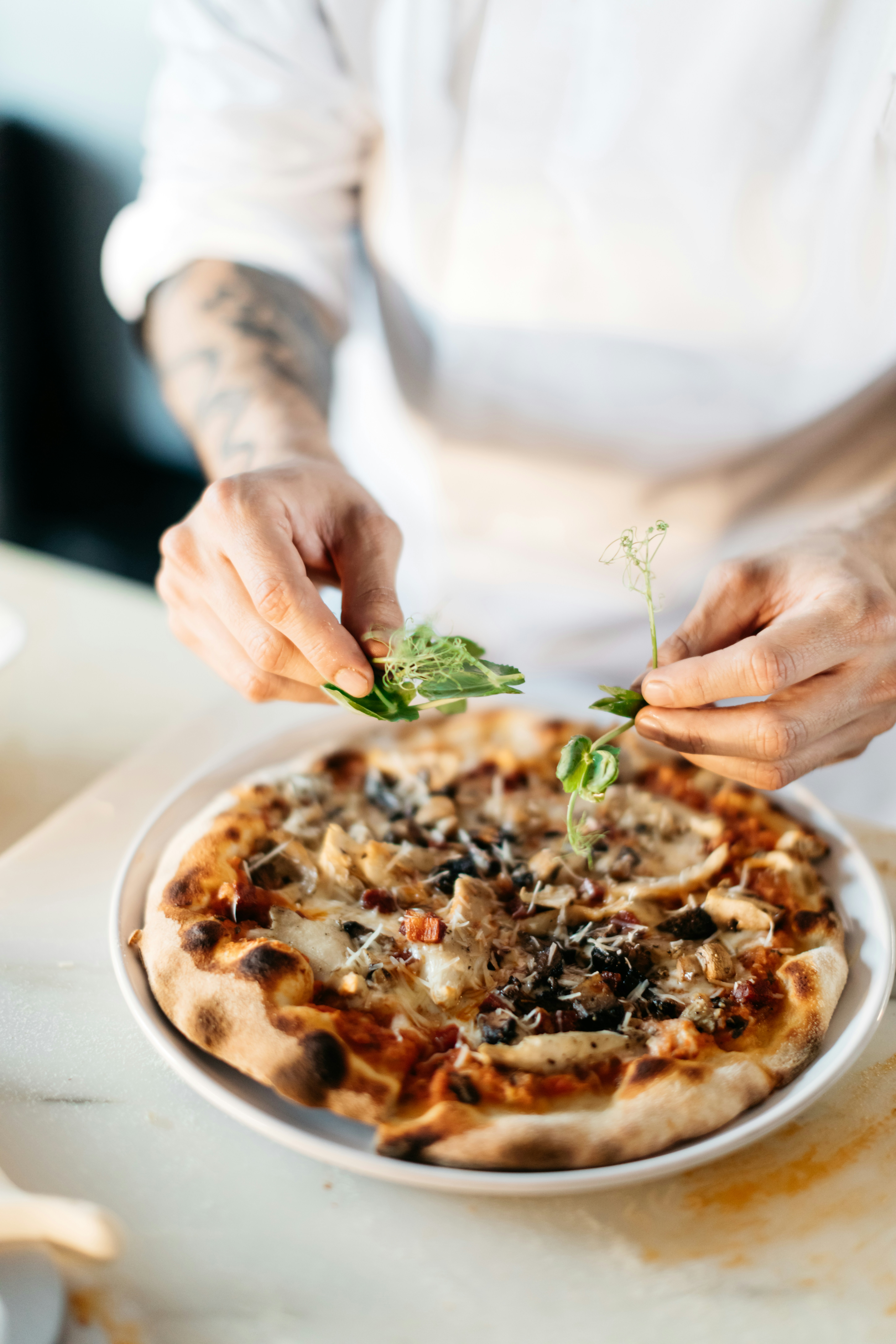 chef prepping pizza with herbs